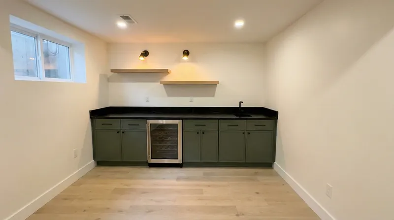 Custom basement wet bar with green cabinets and wine fridge